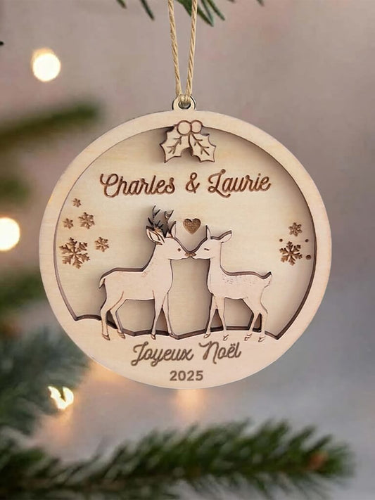 Boule de Noël en bois personnalisée motif Couple de Biches, suspendue dans un sapin décoré.