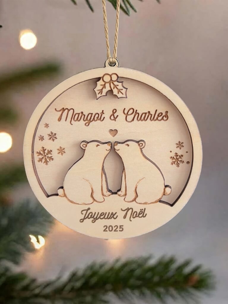 Boule de Noël en bois personnalisée motif Couple d’Ours, suspendue dans un sapin décoré.