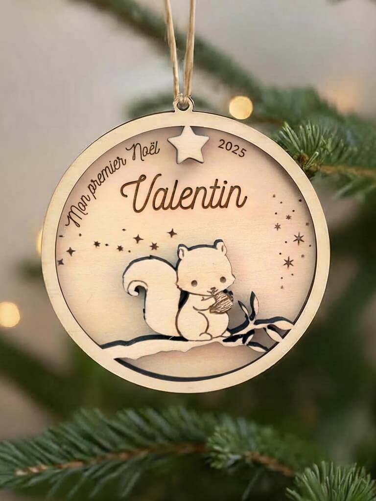 Boule de Noël en bois personnalisée motif Écureuil, suspendue dans un sapin décoré.