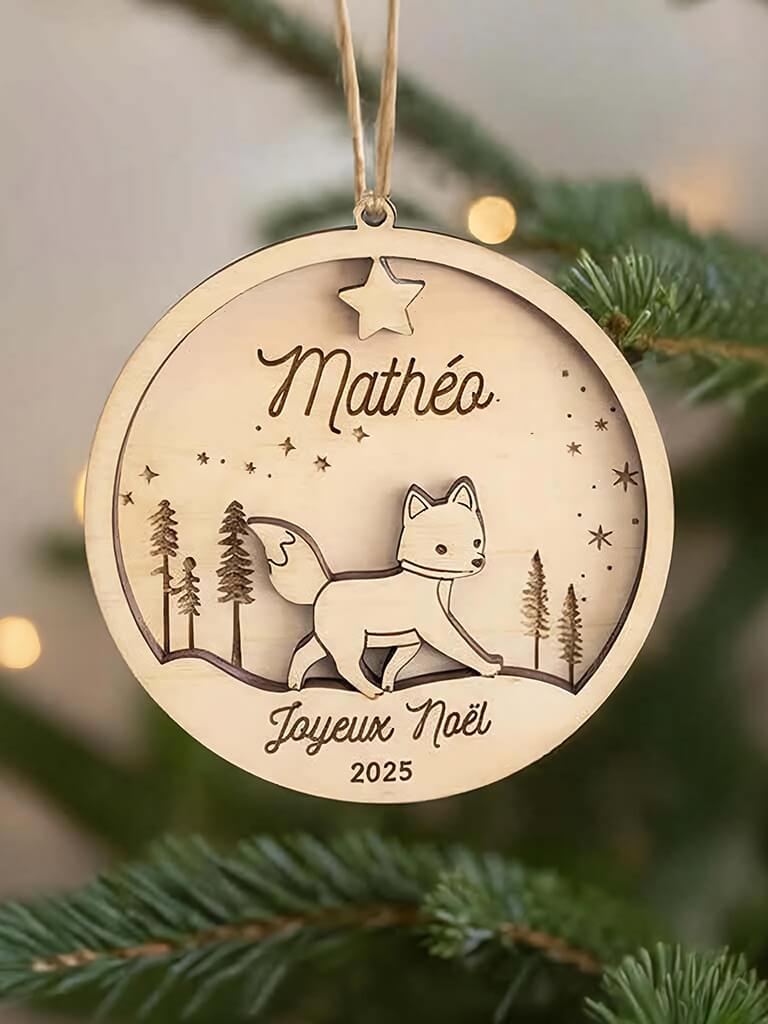 Boule de Noël en bois personnalisée motif Renard, suspendue dans un sapin décoré.