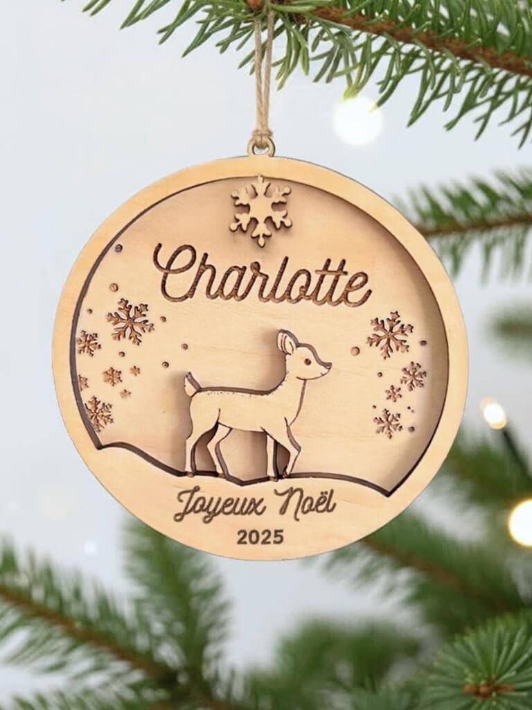 Boule de Noël en bois personnalisée motif Biche, suspendue dans un sapin décoré.