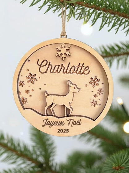 Boule de Noël en bois personnalisée motif Biche, suspendue dans un sapin décoré.