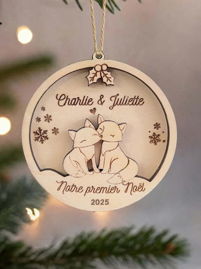 Boule de Noël en bois personnalisée motif Couple de Renards, suspendue dans un sapin décoré.