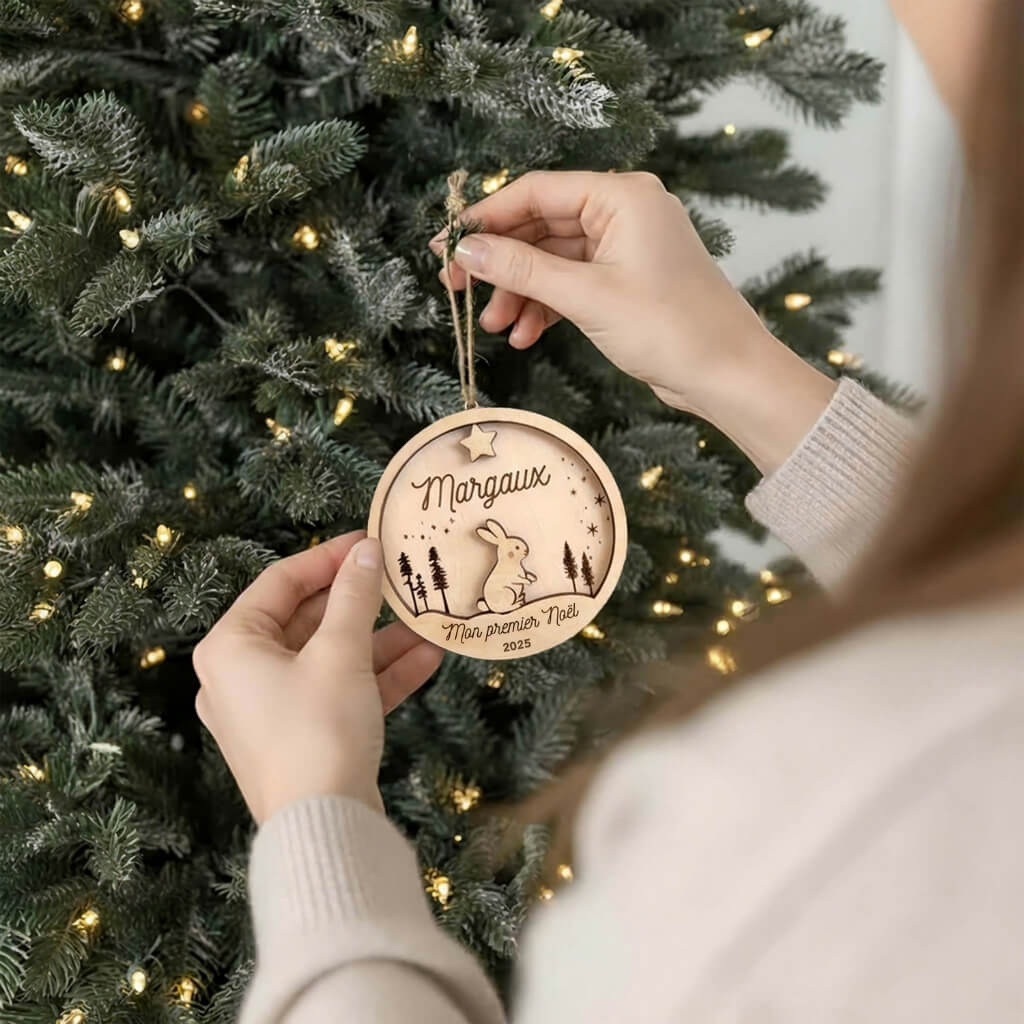 Suspension de Noël en bois motif Lapin, accrochée au sapin par une main.
