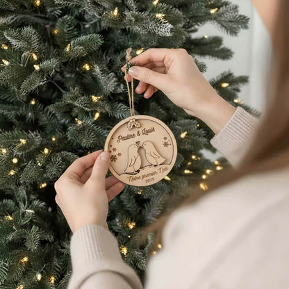 Suspension de Noël en bois motif Couple de Pingouins, accrochée au sapin par une main.