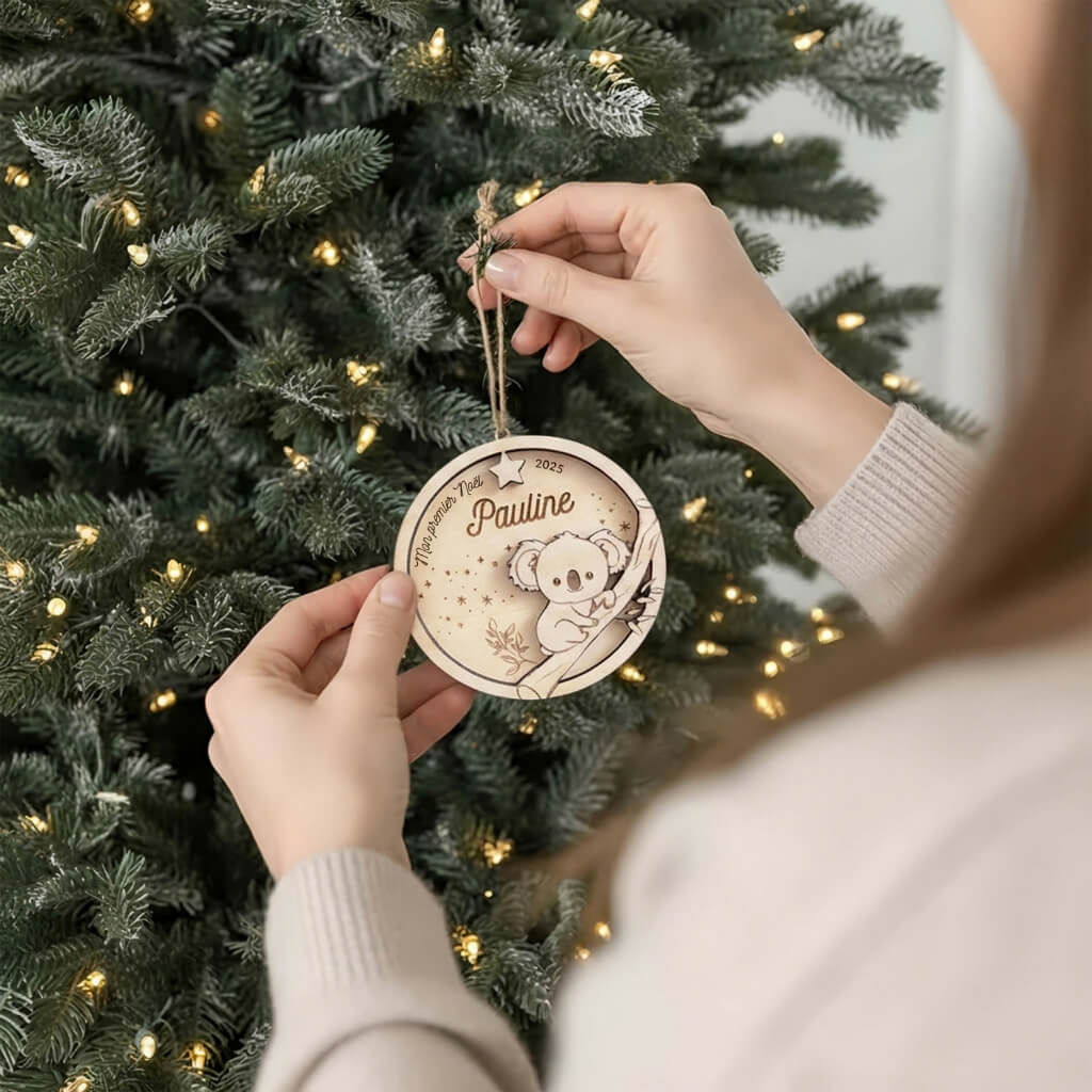 Suspension de Noël en bois motif Koala, accrochée au sapin par une main.